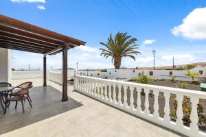 eine Terrasse mit einem weißen Zaun und einem Tisch und Stühlen in der Unterkunft Villa dona Isidora - VipVipVillas in Teguise
