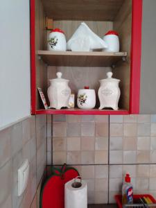 a red shelf with white ceramics in a kitchen at Apartman Mira in Požarevac +14 photos