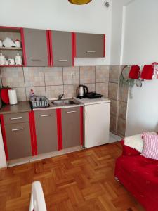 a kitchen with red and white cabinets and a red couch at Apartman Mira in Požarevac