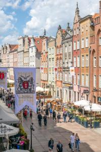 a group of people walking down a street with buildings at Naptun Old Town by Alqueen Apartments in Gdańsk