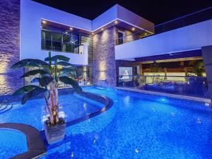 a large swimming pool with a palm tree in front of a building at G R A N D C H A L E T in Salalah