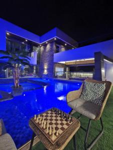 a game of chess on a table next to a pool at night at G R A N D C H A L E T in Salalah
