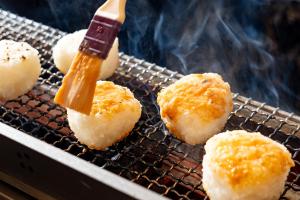 a person cooking food on a grill with a stick at KAMENOI HOTEL Kusatsu Yubatake in Kusatsu