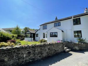 a white house with a stone wall at Mill House in Braithwaite