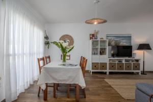 a dining room with a table with chairs and a tv at Nest by the Lagoa, Carvalhal in Carvalhal