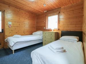 two beds in a room with wooden walls at Sycamore Lodge in Swadlincote