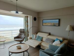 a living room with a couch and a large window at Gezellig appartement met zeezicht en garage in Nieuwpoort