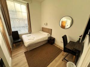 a small room with a bed and a mirror at Somerset Hotel Baker Street London in London