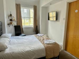 a bedroom with a bed and a chair and a window at Somerset Hotel Baker Street London in London