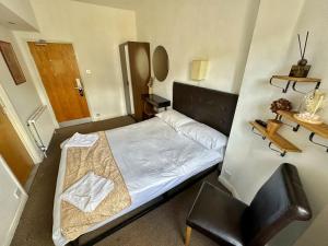 a small bedroom with a bed and a chair at Somerset Hotel Baker Street London in London
