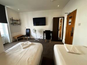 a hotel room with two beds and a flat screen tv at Somerset Hotel Baker Street London in London