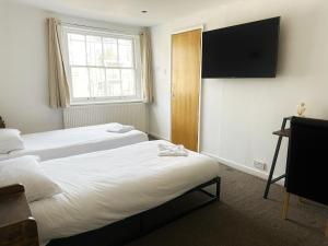 a hotel room with two beds and a flat screen tv at Somerset Hotel Baker Street London in London