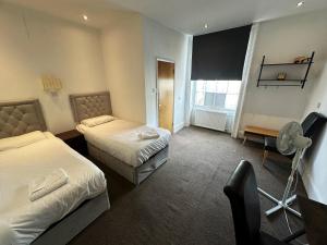 a hotel room with two beds and a television at Somerset Hotel Baker Street London in London