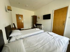a hotel room with two beds and a television at Somerset Hotel Baker Street London in London