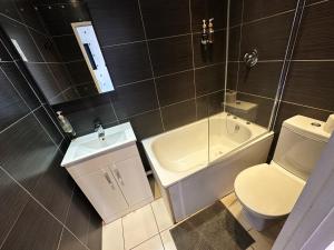 a bathroom with a toilet and a sink and a tub at Somerset Hotel Baker Street London in London