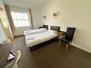 a room with two beds and a desk and a chair at Somerset Hotel Baker Street London in London