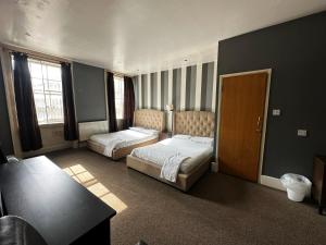a hotel room with two beds and a table at Somerset Hotel Baker Street London in London