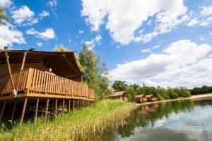 a building with a deck next to a river at Glamping BreeBronne in Maasbree