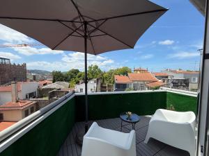 a balcony with an umbrella and two chairs and a table at Apartments Historic Center • Collection by Perpetual Relax in Braga