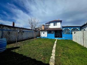 Un patio con una casa azul y una valla. en Vila Calut de mare Jurilovca, en Jurilovca