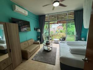 a bedroom with a bed and a couch and a window at Alura Guesthouse in Kata Beach