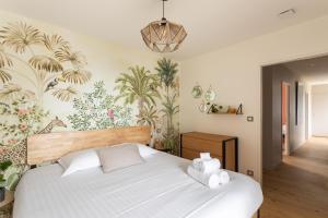 a bedroom with a large bed with a tropical wallpaper at Villa Ker Jade - vue sur la mer in Lancieux +19 photos
