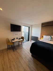a bedroom with a bed and a table and a tv at The Suites, Ormskirk - Rooms by Vici in Ormskirk