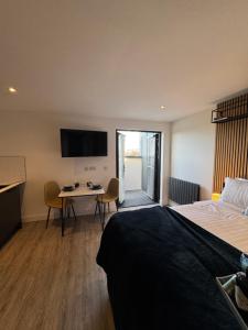 a hotel room with a bed and a table and a television at The Suites, Ormskirk - Rooms by Vici in Ormskirk