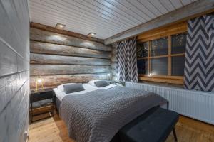a bedroom with a bed and a wooden wall at Kuukkeli Log Houses Aurora Resort in Saariselka