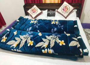un letto con un piumone blu e fiori sopra di Vaishnavi Homestay Yamunotri a Kharsālī