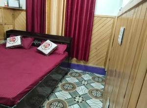 un letto in una stanza con tende rosse e un pavimento di Vaishnavi Homestay Yamunotri a Kharsālī