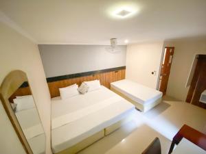 a small room with a white bed and a mirror at Tropika Beach Thulusdhoo in Thulusdhoo