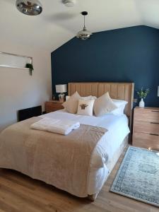 a bedroom with a large bed with a blue wall at The Beehive Inn Hotel in Bury Saint Edmunds +4 photos