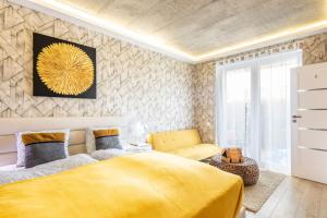 a bedroom with a yellow bed and a chair at BalatonGardens Apartman in Balatonudvari