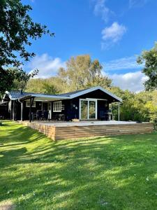 a black house with a wooden deck in a yard at Holiday Home With Views Of Nature In Ertebølle in Farsø