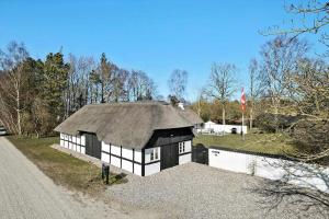 a black and white building with a roof at Restaureret Bondehus Nær Kattegat Med Stor Have in Hadsund