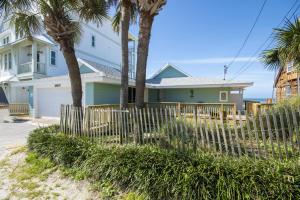 a house with palm trees in front of a fence at Island Time- Wonderful Private Beachfront Home - Beautiful!!! in Panama City Beach