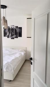 a white bedroom with a bed and pictures on the wall at Cozy apartment in Baia Mare