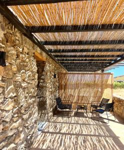 two chairs sitting on a patio with a stone wall at Farm House Near Of Merhia Beach In Mykonos in Merchia Beach