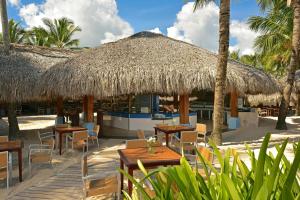 een restaurant met tafels en stoelen en een rieten parasol bij Iberostar Punta Cana in Punta Cana