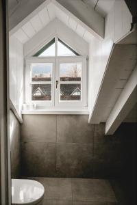 an attic bathroom with a window and a toilet at Seehotel Brandauer's Villen in Strobl +108 photos