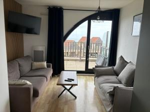a living room with a couch and a table and a window at Appartement à la Naturelle in Wimereux