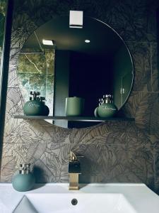 une salle de bain avec un lavabo et un miroir dans l'établissement La Cabane du Prestadou - Bain nordique et Sauna, à Arcambal 26 autres photos