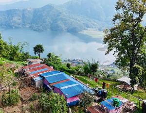 un gruppo di edifici su una collina con vista su un lago di Hom's Homestay & Farmstay Sarangkot Pokhara a Pokhara