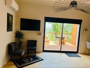 un salon avec une porte coulissante en verre donnant sur un patio dans l'établissement La Cabane du Prestadou - Bain nordique et Sauna, à Arcambal