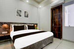 a bedroom with a large bed and a wooden door at Hotel O Shivoham in Indirapuram