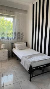 sypialnia z łóżkiem z czarno-białą ścianą o paskach w obiekcie Pavlina w mieście Kallithea
