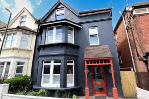 a blue house with a red door on a street at The Albany Rooms Bexhill in Bexhill