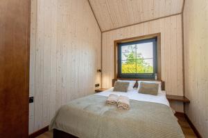 a bedroom with a bed with two slippers on it at Domki Apartamentowe Chmielówka 2 in Chmielno