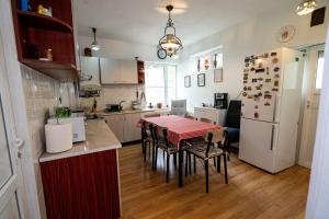 a kitchen with a table with chairs and a refrigerator at Retro Green Cottage with a Barkyard - Pet Friendly in Braşov